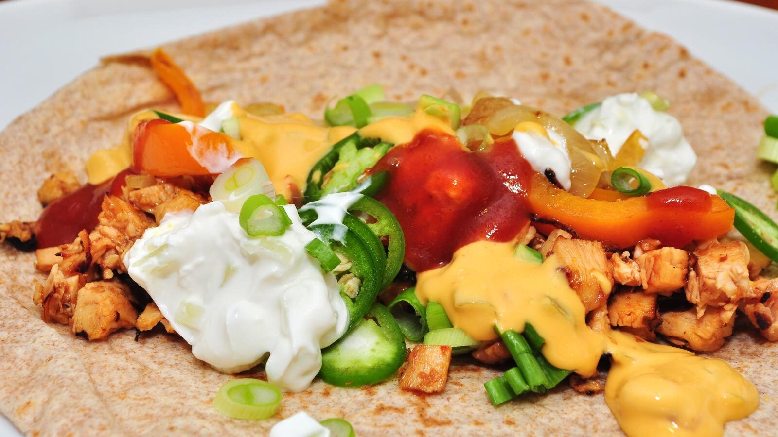 Chicken fajita on a tortilla with peppers and salsa