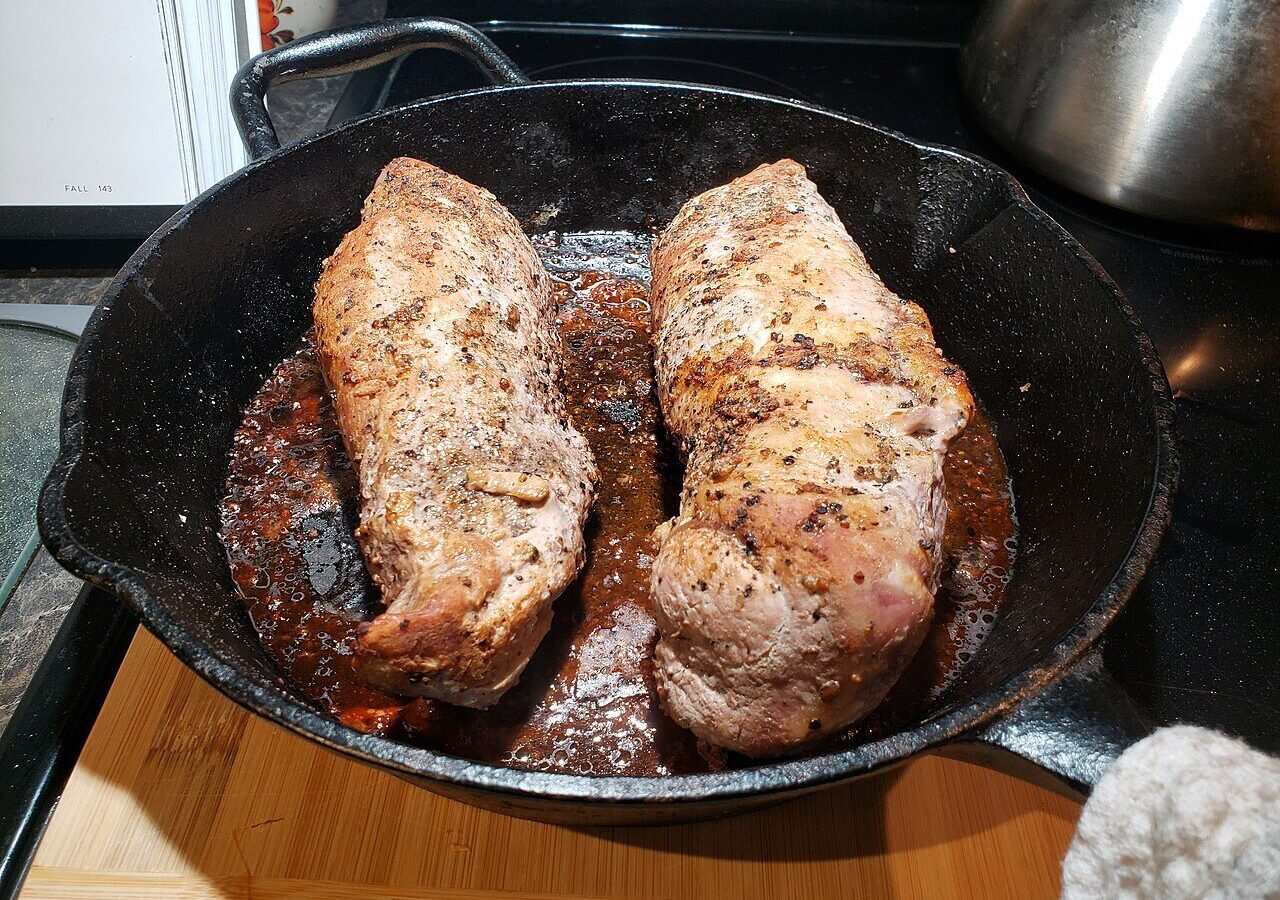 Seared pork tenderloin with browned pan fond in a cast iron skillet