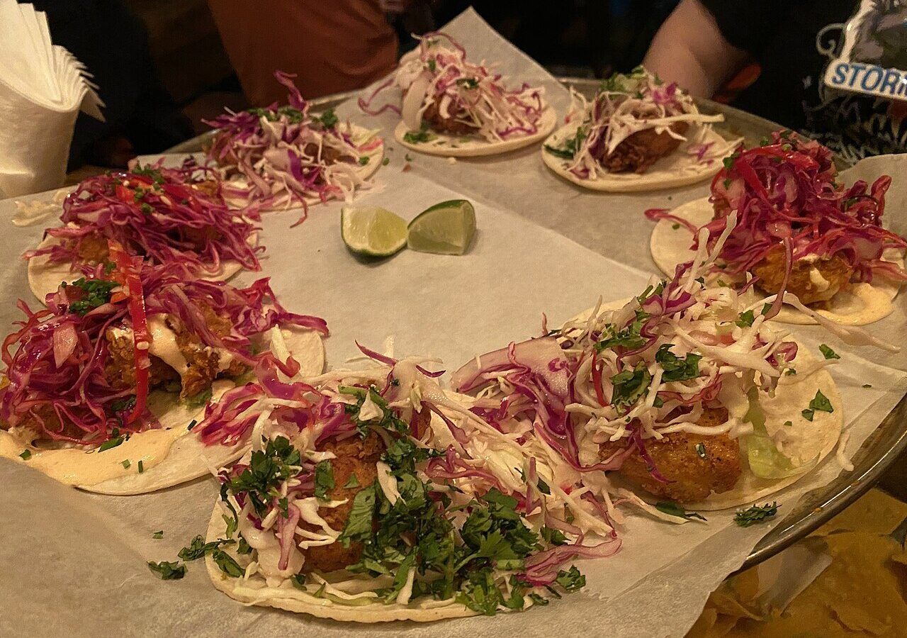 Fish tacos topped with shredded red cabbage and herbs on a plate