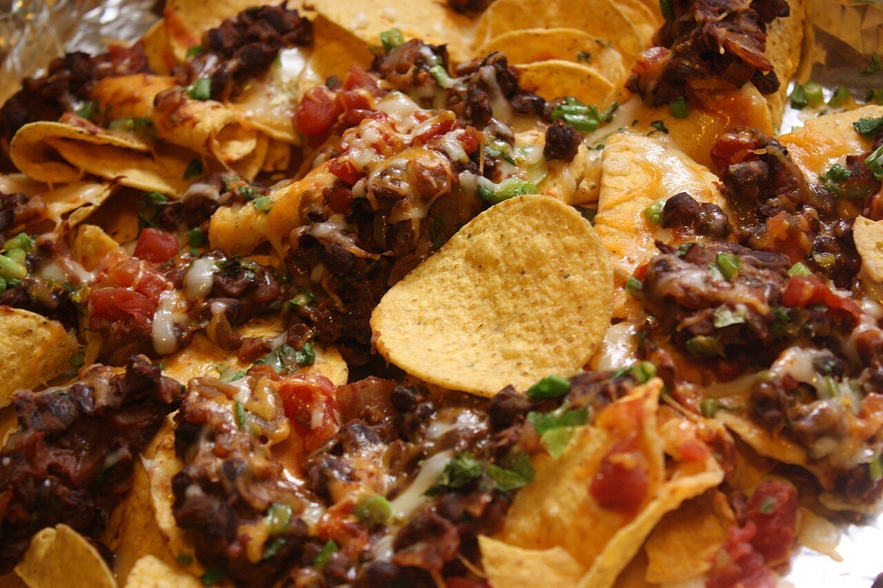 Loaded nachos with seasoned beef, beans, melted cheese, and tomatoes